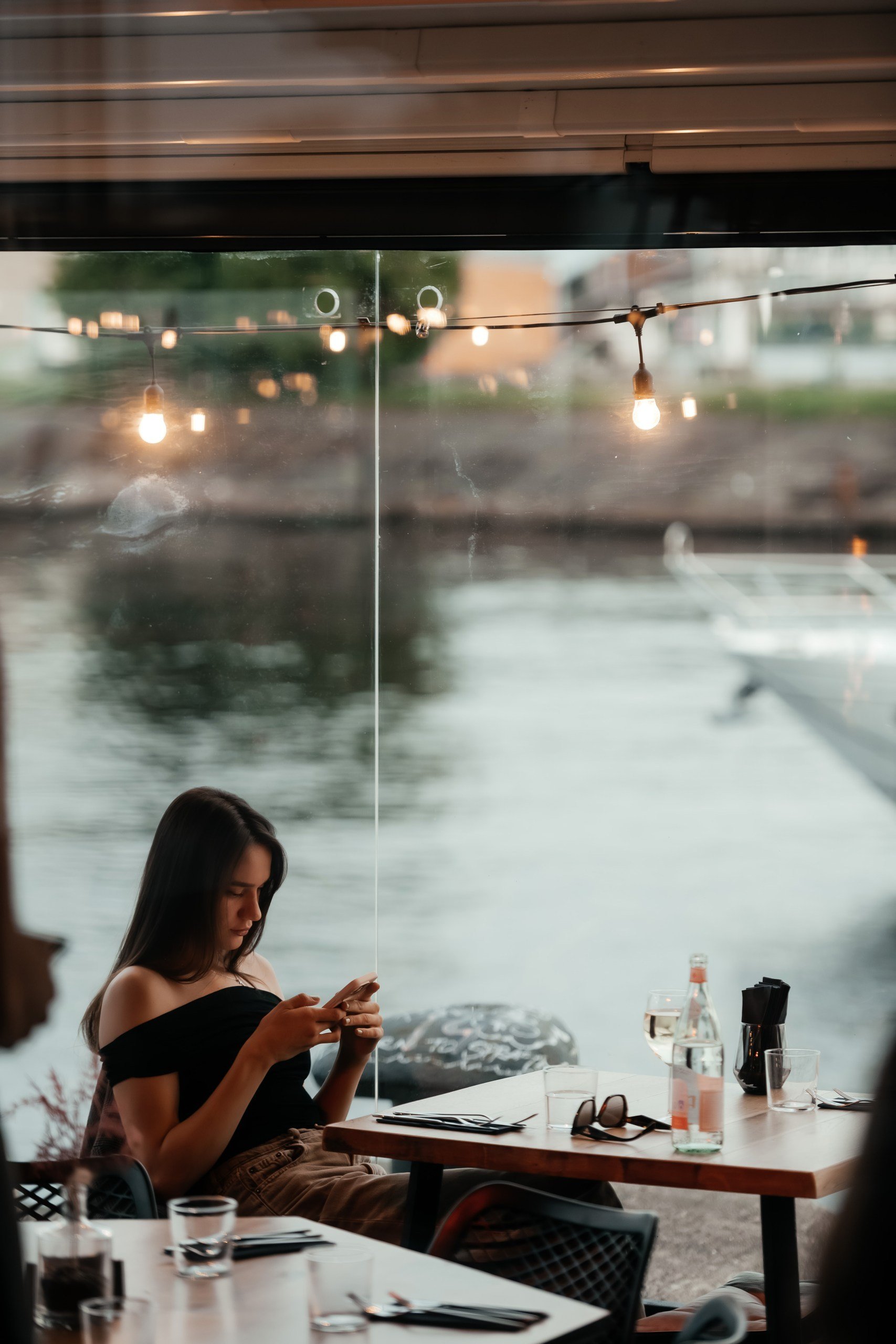A riverside table by the glass overlooking the Daugava at dusk